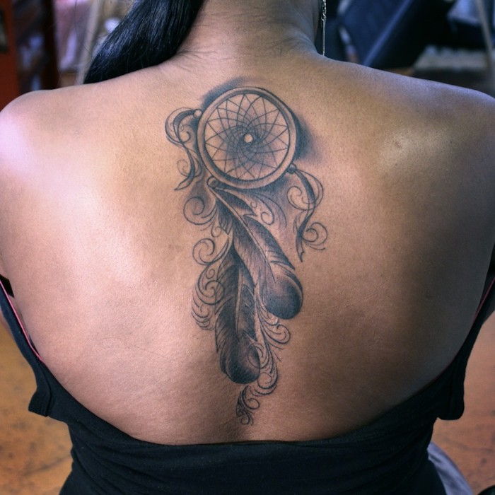 Idea per un tatuaggio nero sul collo di una giovane donna - un acchiappasogni nero con due piume nere