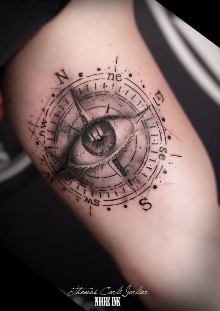 et stort svart øye og et stort svart kompass - ide for en flott svart tatoveringskompass på den ene siden
