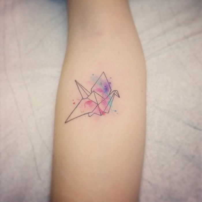to jest pomysł na temat tatuażu origami - ręka z małym kolorowym tatuażem origami - latający kolorowy ptak