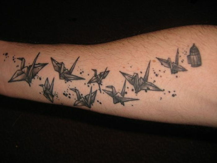 czarna klatka i wiele małych czarnych latających ptaków origami - pomysł na tatuaż origami na dłoni