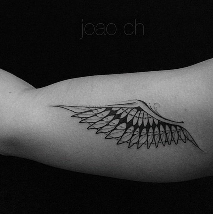 Ręka z małym tatuażem czarnego anioła z długimi czarnymi piórami