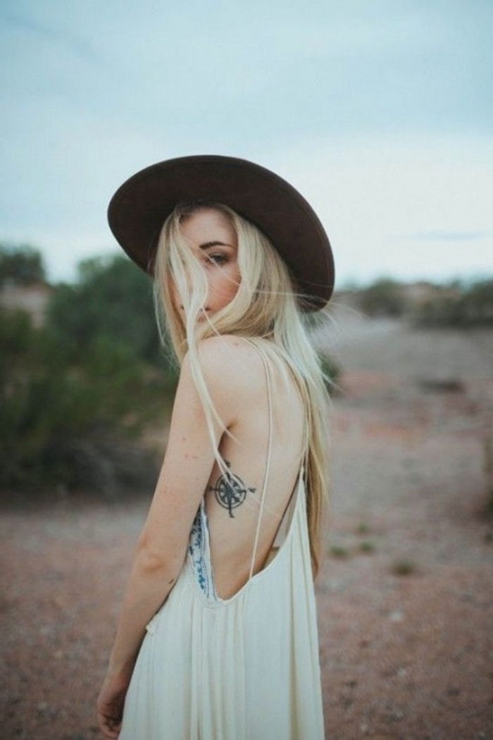 Jauna moteris su juodą skrybėlę ir maža elegantiška tatuiruotė su juodu kompasu