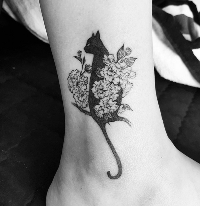 Tutaj znajdziesz świetny pomysł na temat tatuażu kotów na nodze - czarnego kota i białych kwiatów