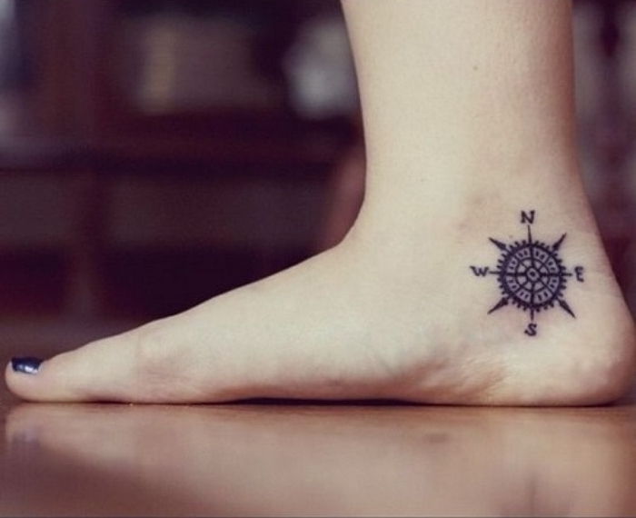ben med en blå neglelakk og en liten mini svart tatovering med et svart kompass på hælen