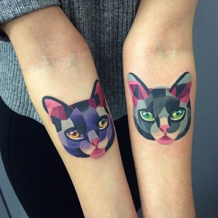 Tutaj pokazujemy obiema rękoma kolorowe tatuaże koty - kot o zielonych oczach i różowym nosie oraz purpurowy kot o pomarańczowych oczach