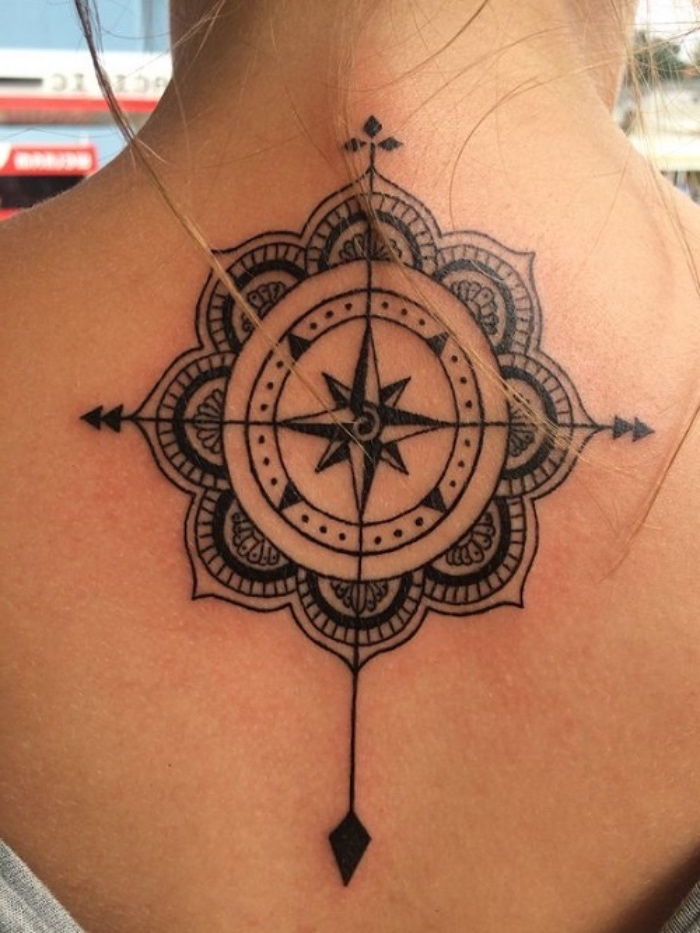 idėja už didelę juodą kompaso tatuiruotę su juodos mandalos kompasu su keturiomis juodomis strėlėmis ant jaunosios moters priekinės dalies