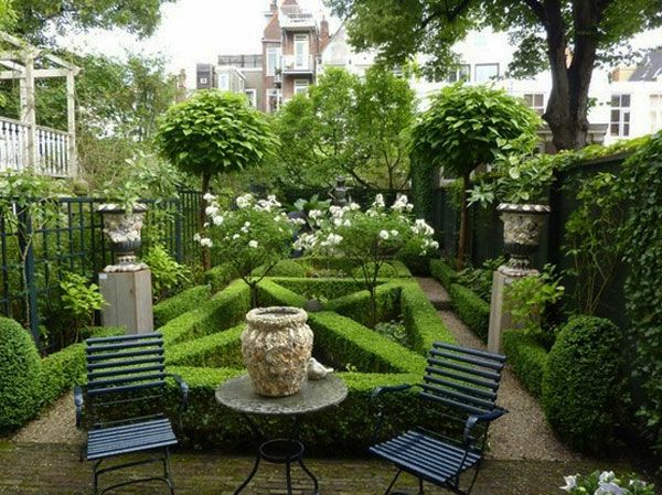 grădină verde cu două scaune negre și multe plante verzi