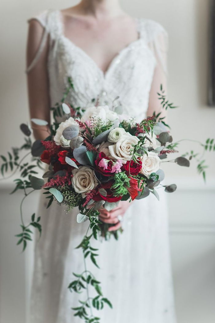 mooie prinses trouwjurk met rode en witte rozen - groene planten - bruidsboeket zomer