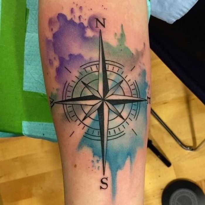 en vacker svart stor tatuering med en svart kompass - en hand med kompasstatuering och färgglada färger