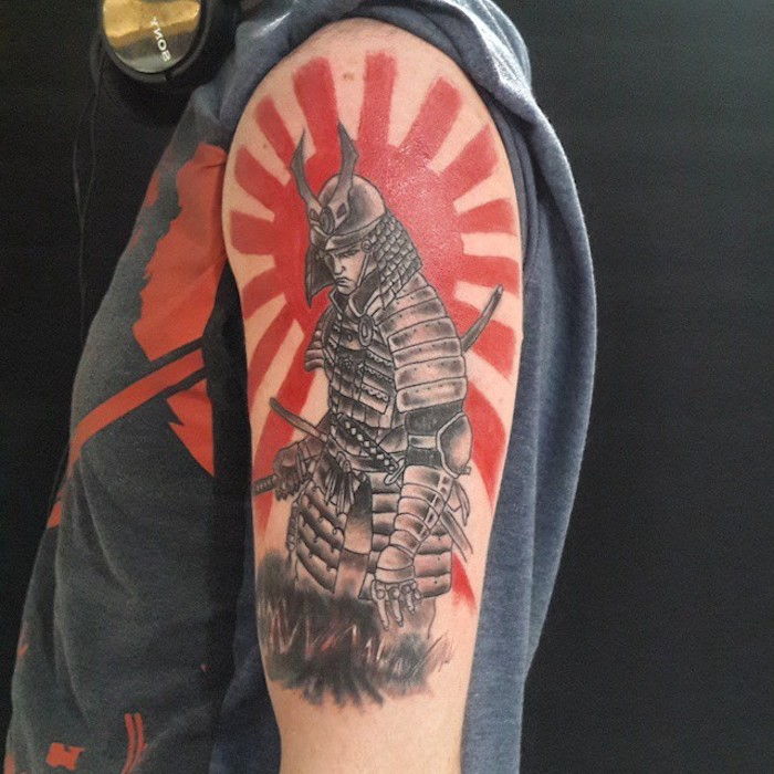 tatuaggio da combattente, t-shirt grigia, sole rosso, uomo con elmo e equipaggiamento