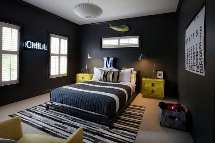 Gençlik odası tasarımı, siyah çizgili duvarlar, sarı başucu masaları, yatağın üstündeki M harfi