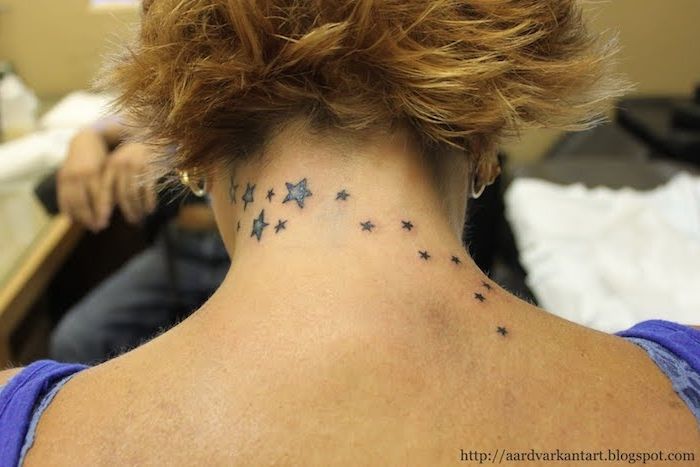 kadın için yıldız dövmesi fikri - arkada küçük ve büyük siyah ve mavi yıldızlarla siyah dövme