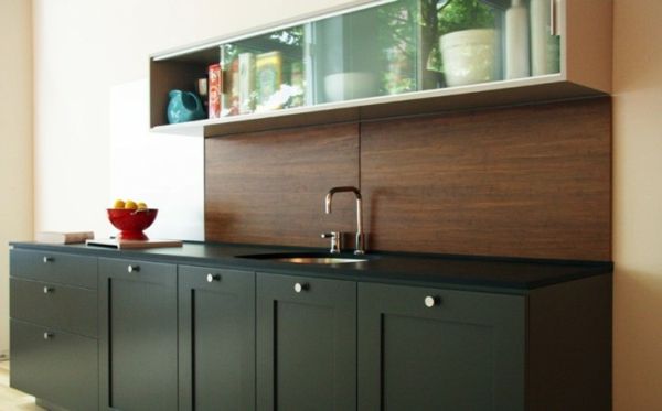 virtuvė su medine atgaline siena ir juodos virtuvės spintelės