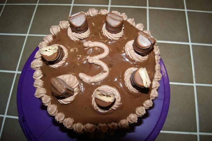 Chokladglasyr barn bar kaka med små blommor av grädde och nummer tre