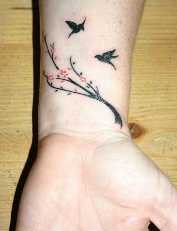 uma pequena tatuagem no pulso de uma mulher, árvore negra, pássaros pretos