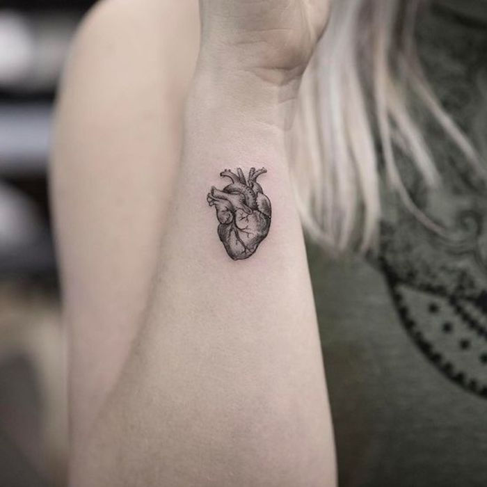 Mulher loira me dando uma mini tatuagem em forma de coração humano
