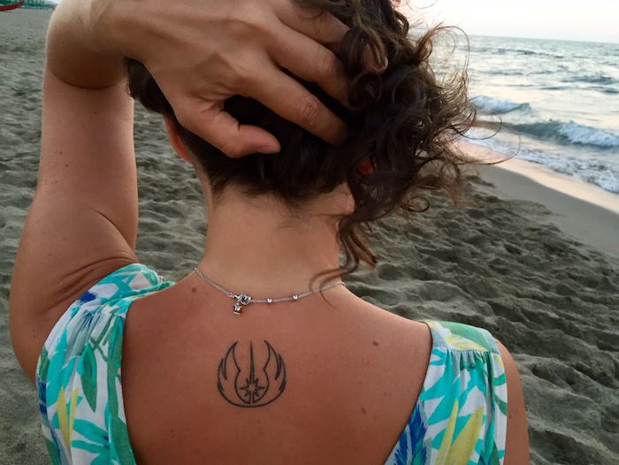 mladá žena s tetovaním hviezdnych vojen s logom malých hviezdnych vojen - mora a pláž s pieskom
