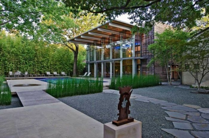 et hus med en moderne hage, glassfasade, et svømmebasseng, skulptur