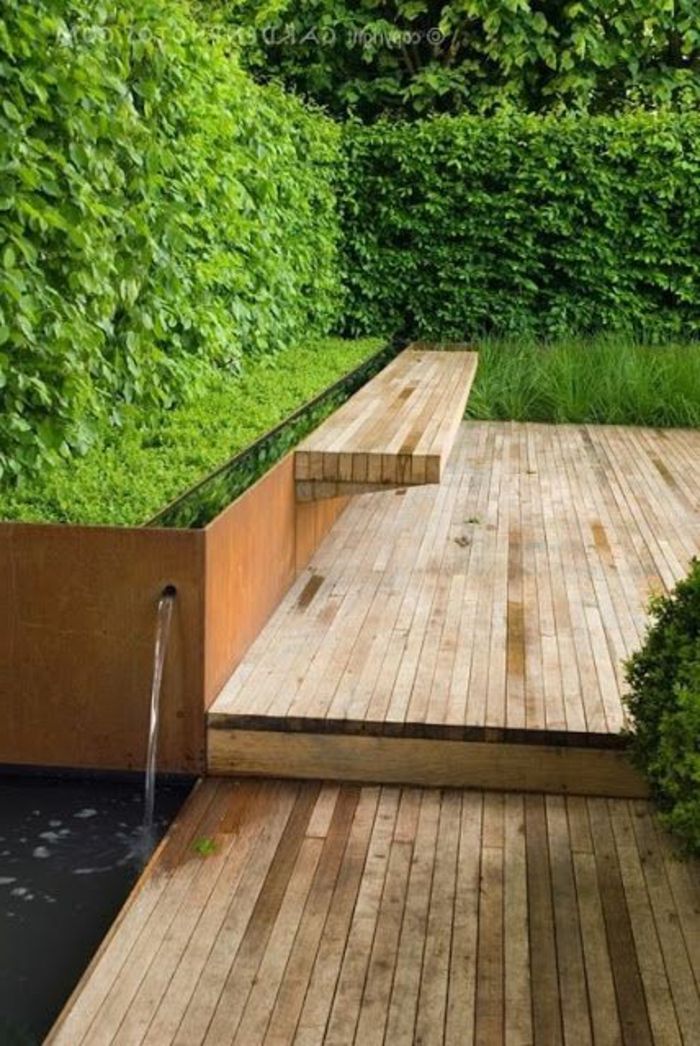 Vattenfunktion, inbyggd bänk Vatten har en grön häck - puristträdgård