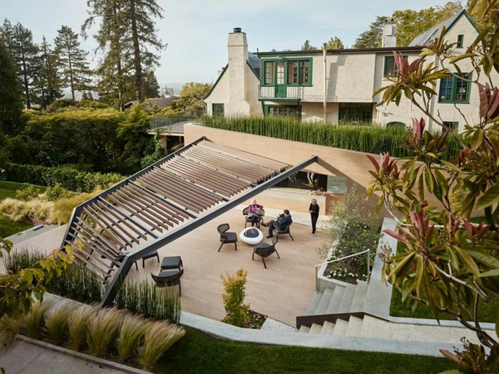 en pergola, snyggt högt gräs, trädgårdsmöbler och hus i minimalistisk stil - moderna trädgårdar
