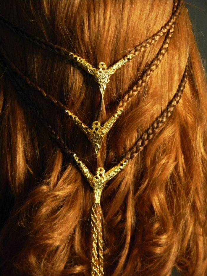 trys mažos nerijos su auksiniais ornamentais ant galų, raudoni plaukai puošti šukuosenos
