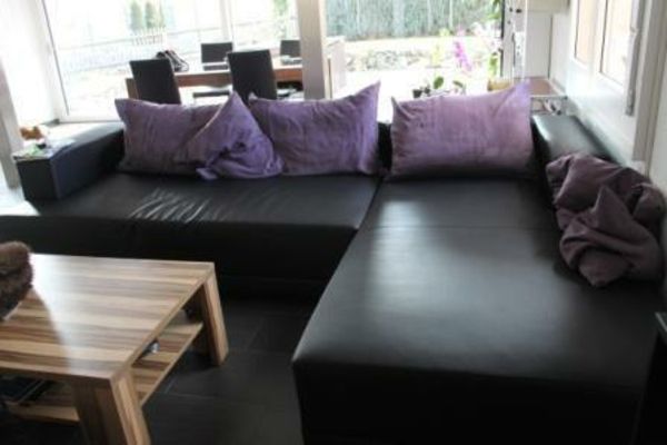 Šiuolaikinė sofa apima purpurinę pagalvę, mažą kambarį