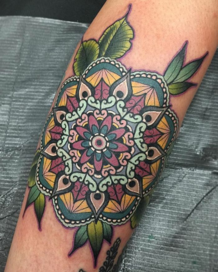 färgad tatuering med många ornament och många gröna blad, vita prickar och svarta konturer