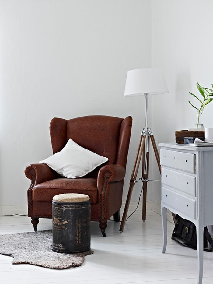 Mobili vintage, soggiorno, idee di interior design, divano in pelle marrone con cuscino decorativo bianco, lampada da terra e cassetto