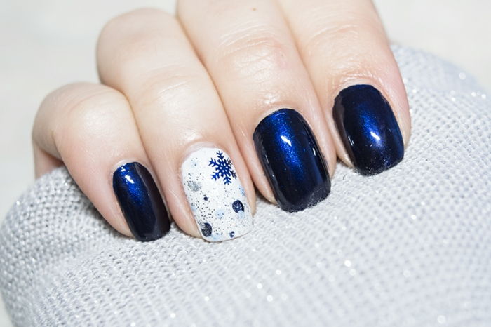 Winterspijkers, donkerblauwe sneeuwvlokken op een witte achtergrond, donkerblauw nagellak, hoekige spijkervorm