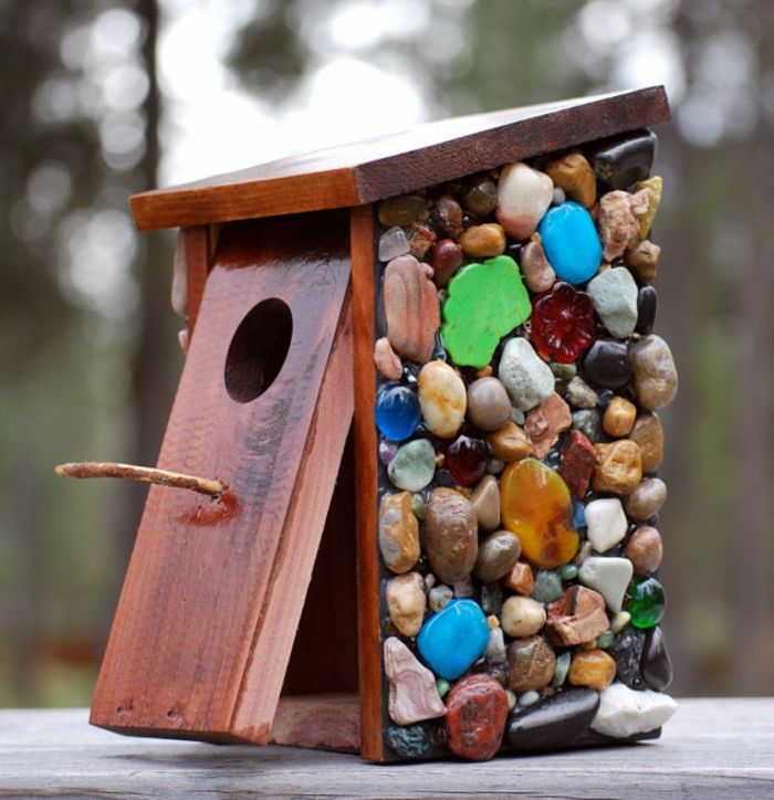Nesting boks laget av tre med fargerike dekorative steiner, birdhouses og vakre hage eller balkong dekorasjon på samme tid
