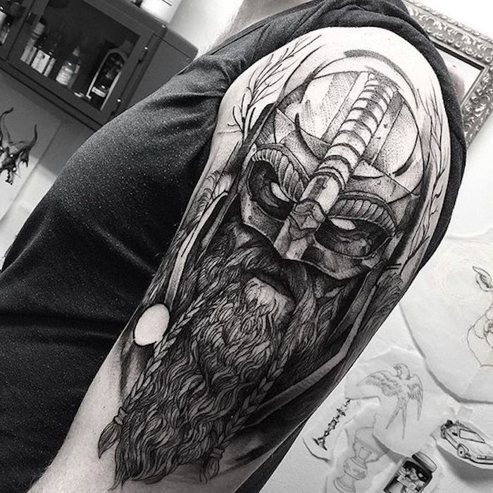 tatuaggio nordico, t-shirt grigia, vichingo con barba lunga e elmo