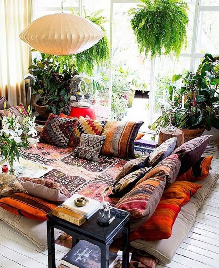 belo leseno tla z majhnimi vzorčnimi odeji, maroške blazine z barvnimi vzorci, številne zelene rastline, dve viseči rastlinji, lestenci iz belega papirja, sprostitveni kotiček s pogledom na teraso