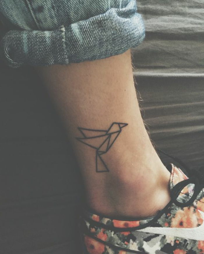 noga z maleńkim mini tatuażem z motywami origami - małym czarnym latającym ptakiem origami