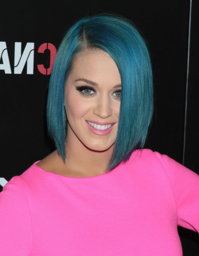 Katy Perry con acconciatura blu bob, labbra rosa tenue, mascara nera, vestito in colori vivaci