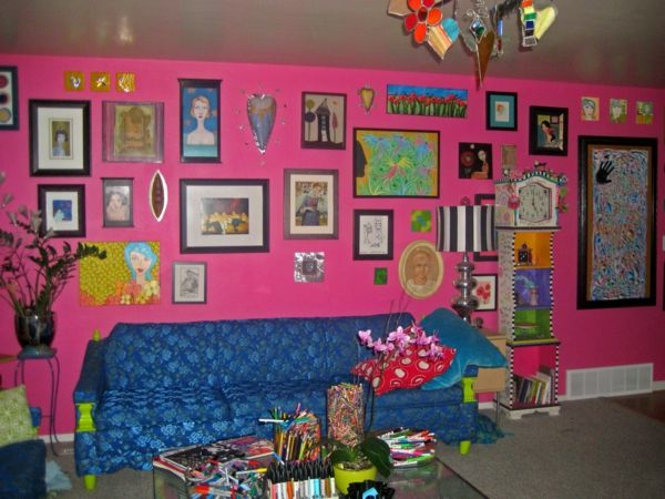 rosa vägg-färg-och-många-bilder-på-vägg-soffan i blått