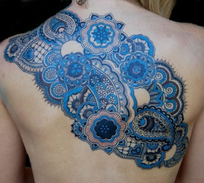 Kvinna med axel- och ryggtatuering med små mandalor i många nyanser av blåa, små ornament i mörk färg