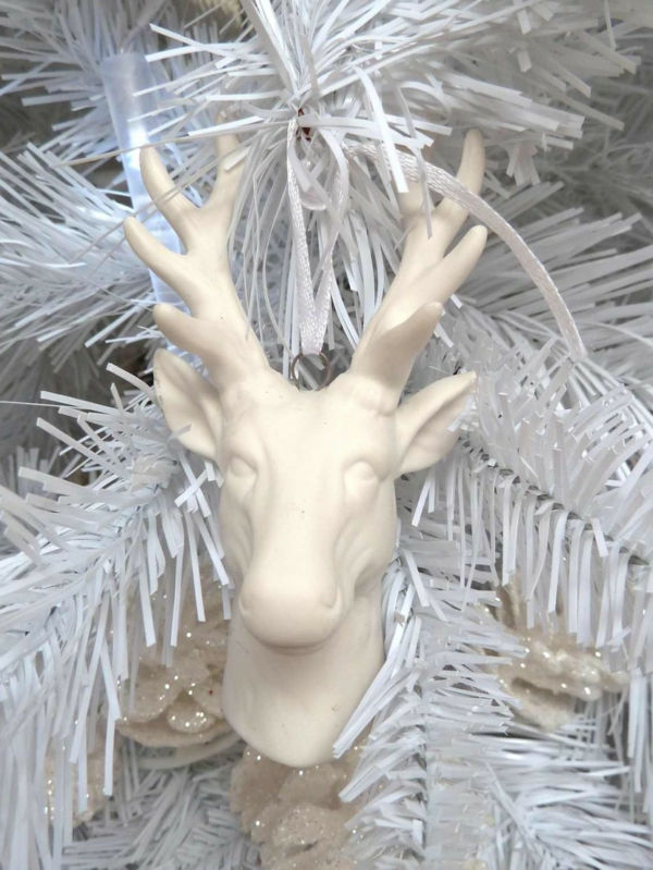 białe świąteczne dekoracje - biała jodła z głową jelenia na niej