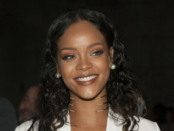 Orecchini di perle con capelli ricci neri, rossetto marrone - immagini di Rihanna