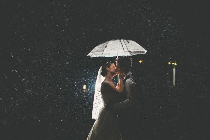 romantična poročna fotografija neveste in ženina poljub v dežju
