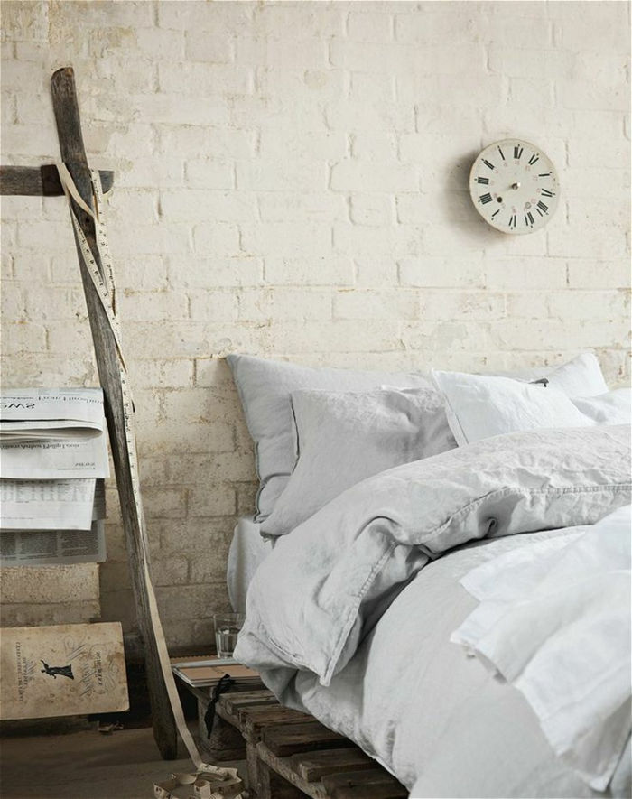 enkel sovrum inredning europallar säng vitt linne väggklocka-klassisk modell vita tegelväggar