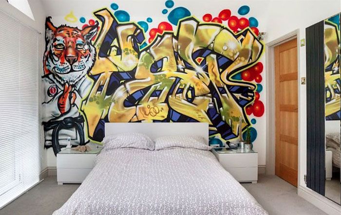 Gençler için yataklar, beyaz bir yatak, grafiti dekore edilmiş oda, iki başucu masası
