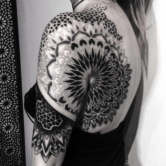 komplicerad punktteknik med tatueringar, olika geometriska figurer, svart mandala med geometriska motiv, svarta gardiner med vit mandala tryck, kvinna med ljust långt hår med svart topp