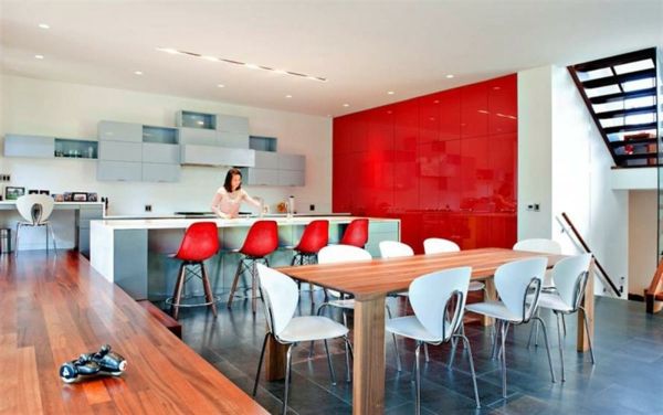 didžiulė virtuvė-daugelis raudonų barstolių šalia didelio masyvo medžio stalo