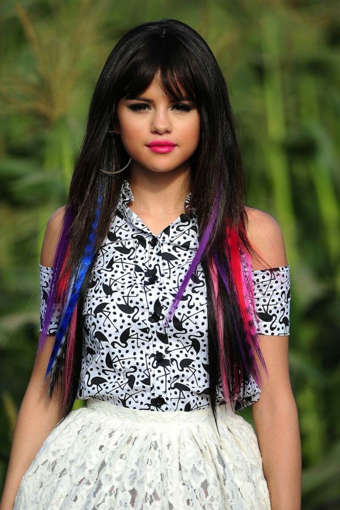 Selena Gomez s farebnými prameňmi, dlhé vlasy s náramkami, svetlá rúž, čierna riasenka