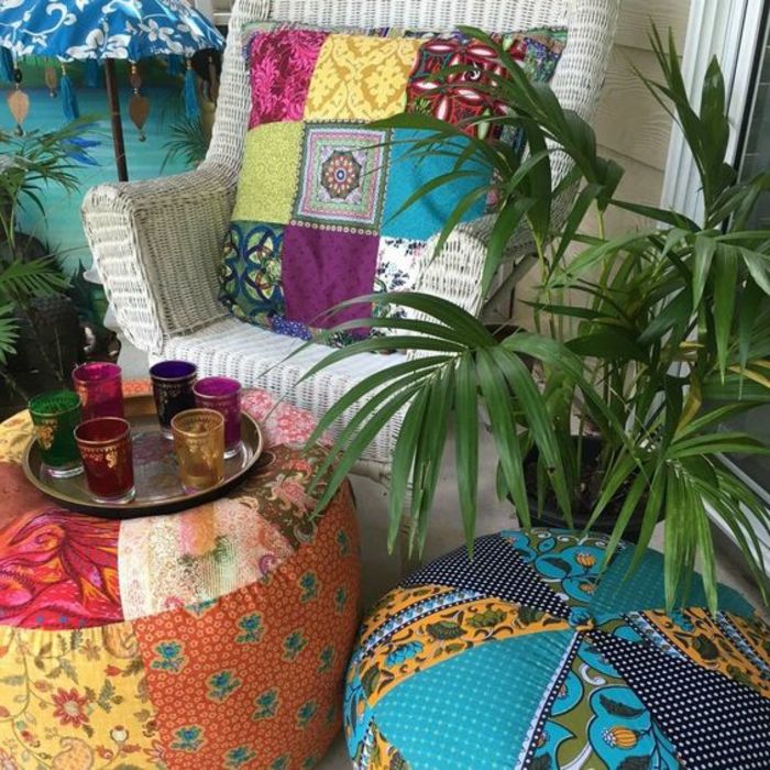 dva velika puffs s tkaninskimi veznimi oblogami z barvitimi vzorci, belim vrbovim stolom z barvitim klobučastim blazino, dvema zelenima rastlinama