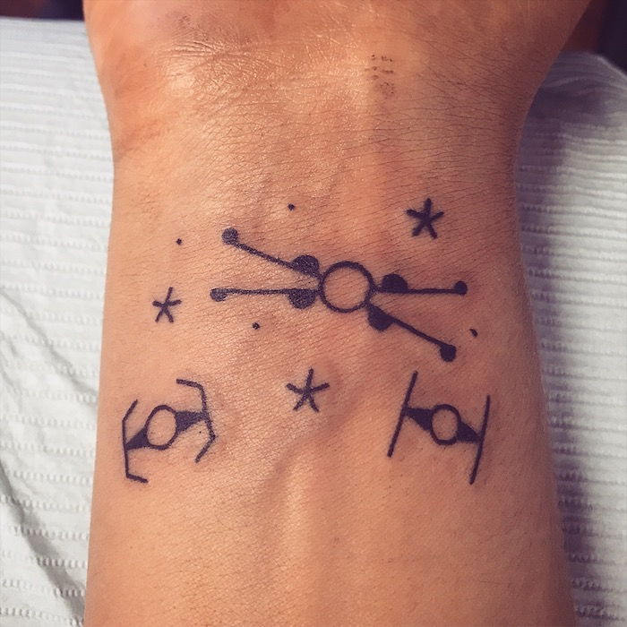malé drobné tetovanie lietajúcich vesmírnych lodí a malé čierne hviezdy a planéty