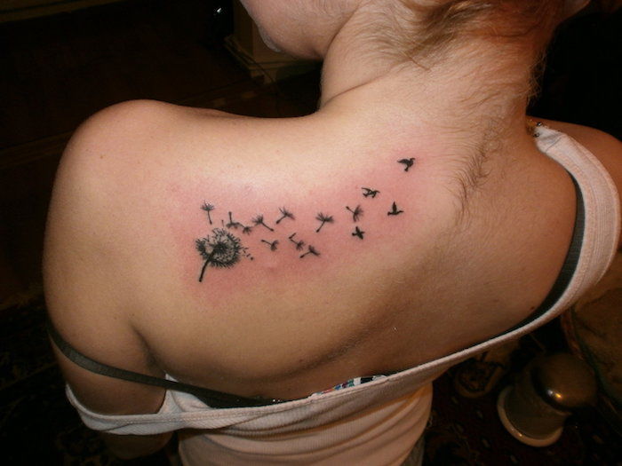 Kvinna med en liten tatuering på hennes axel, svart och grå tatuering