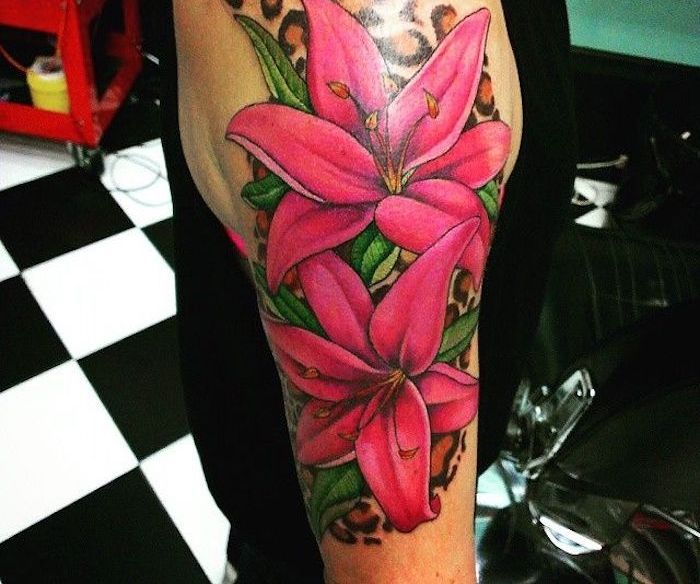 Tatuiruotė reiškia didelę spalvotą tatuiruotę su rožinėmis lelijomis