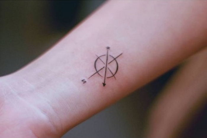 liten vakker tatovering på håndleddet med kompass og svarte små piler