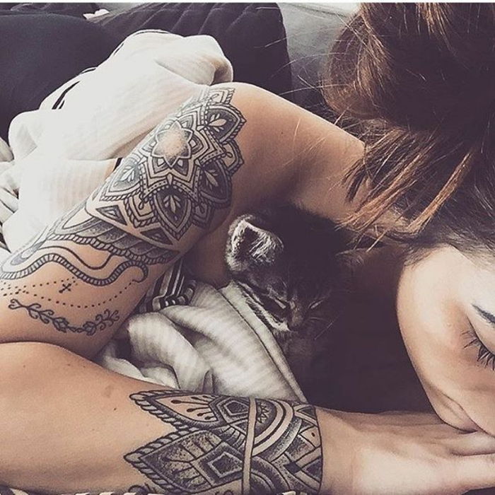ung tjej med långt tjockt mörkt brunt hår och smala armar, en övre och en underarm tatuering med stammotiv och symboler, med ett nätverk av hjärtan och spiraler